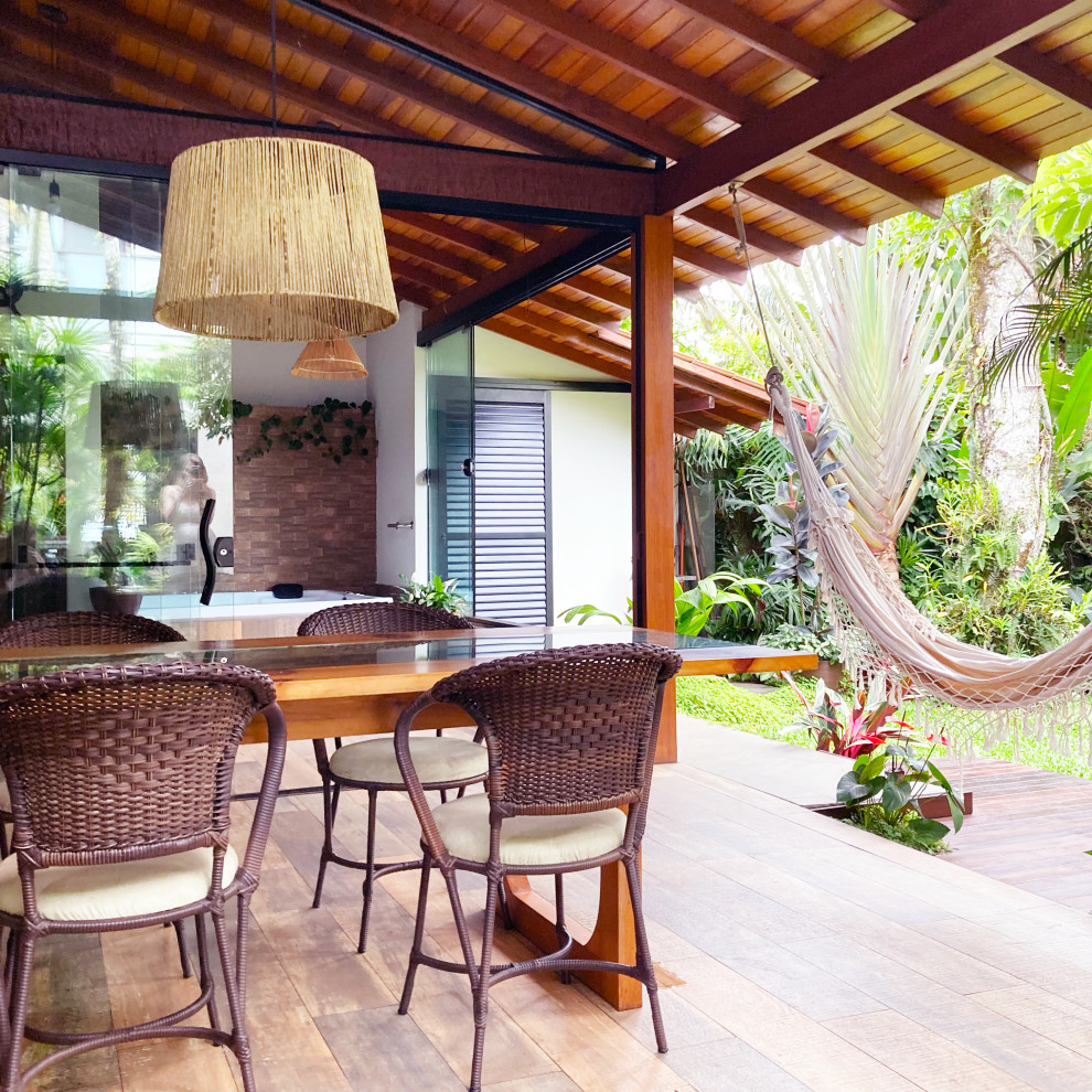 Ejemplo de terraza tropical pequeña en patio trasero y anexo de casas con suelo de baldosas