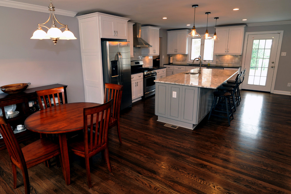 Mid-sized transitional l-shaped medium tone wood floor open concept kitchen photo in Atlanta with a double-bowl sink, white cabinets, quartzite countertops, white backsplash, stainless steel appliances and an island
