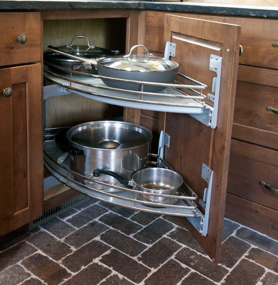 Photo of a mid-sized country u-shaped eat-in kitchen in Philadelphia with a farmhouse sink, flat-panel cabinets, medium wood cabinets, granite benchtops, beige splashback, subway tile splashback, stainless steel appliances, brick floors and no island.
