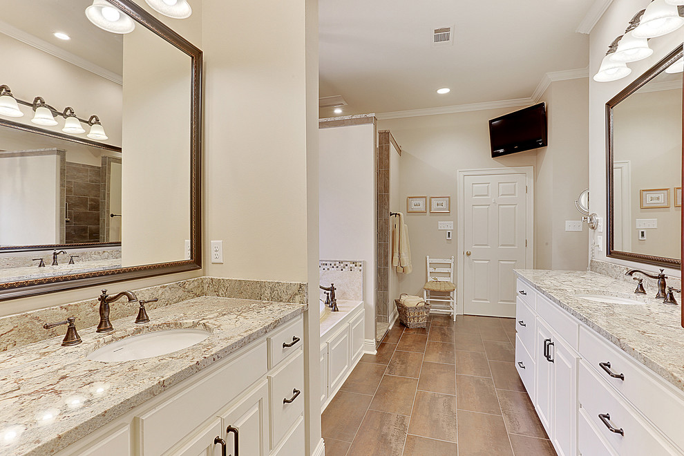 This is an example of a large traditional master bathroom in New Orleans with an undermount sink, raised-panel cabinets, white cabinets, granite benchtops, a drop-in tub, a double shower, brown tile, ceramic tile, beige walls and ceramic floors.