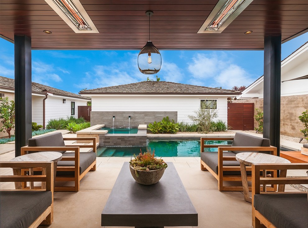 Photo of a small contemporary courtyard rectangular lap pool in Orange County with a water feature and concrete slab.