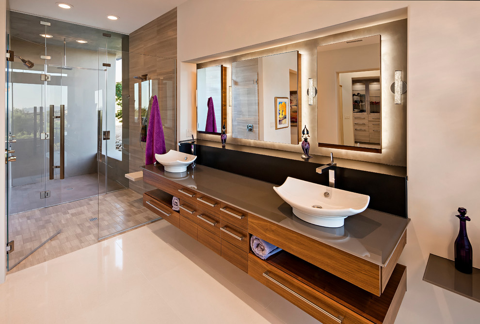 Photo of a mid-sized modern master bathroom in Phoenix with flat-panel cabinets, dark wood cabinets, a corner tub, an open shower, a one-piece toilet, beige walls, ceramic floors, a pedestal sink and glass benchtops.