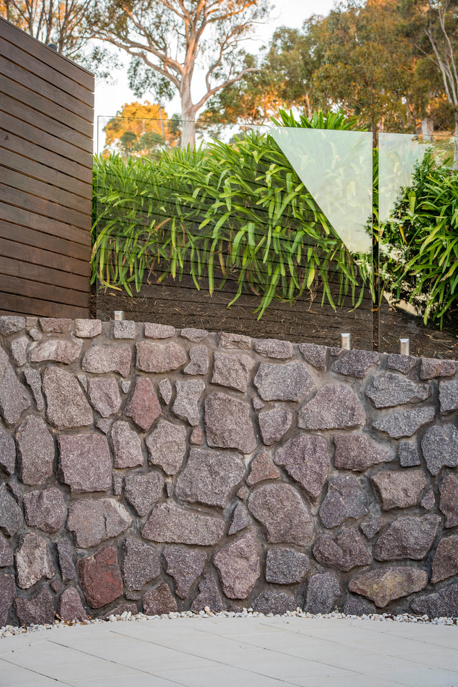 This is an example of a large contemporary backyard pool in Canberra - Queanbeyan with natural stone pavers.