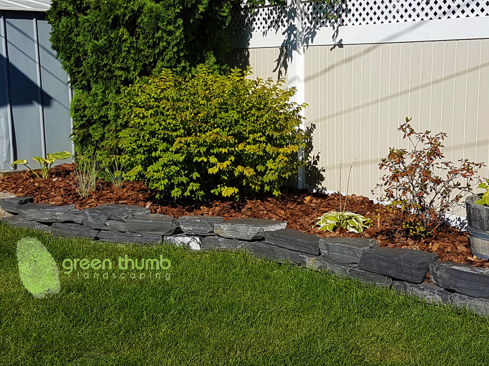 Design ideas for a rustic full sun backyard stone retaining wall landscape in Edmonton for summer.