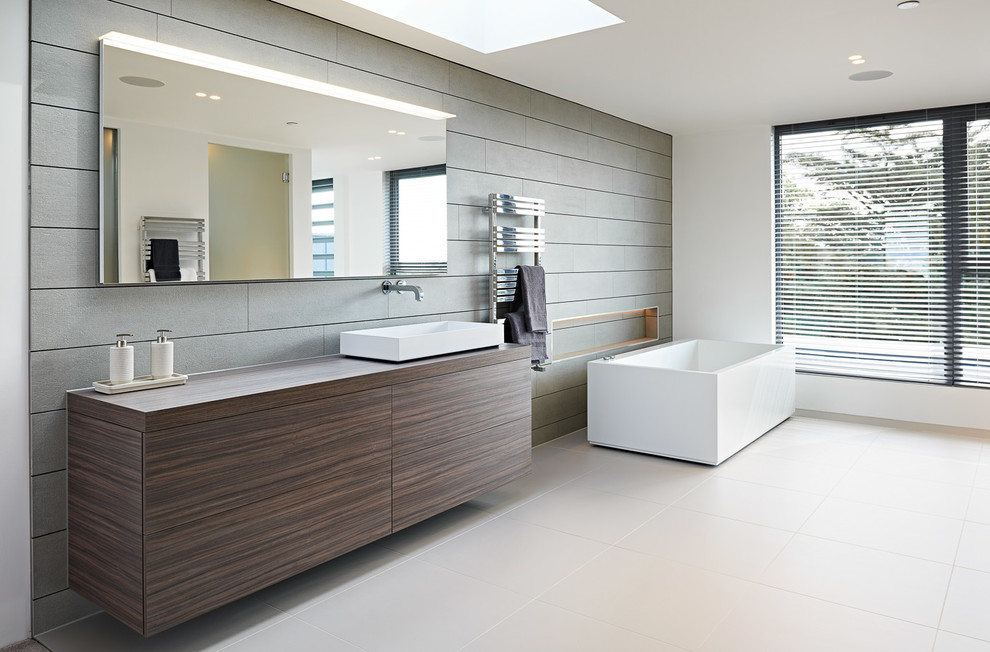 Design ideas for a large contemporary master bathroom in Dorset with flat-panel cabinets, grey cabinets, a freestanding tub, an open shower, a one-piece toilet, gray tile, porcelain tile, grey walls, porcelain floors and a console sink.