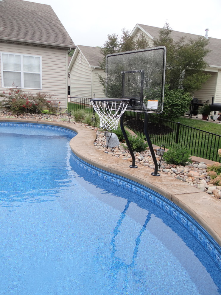 Design ideas for a mid-sized contemporary backyard custom-shaped pool in St Louis with stamped concrete.