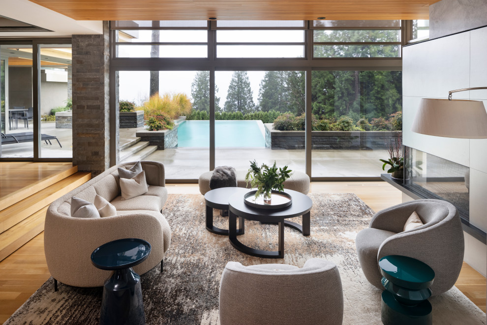 Geräumiges, Fernseherloses, Offenes Modernes Wohnzimmer mit braunem Holzboden, Tunnelkamin, Kaminumrandung aus Beton und orangem Boden in Vancouver