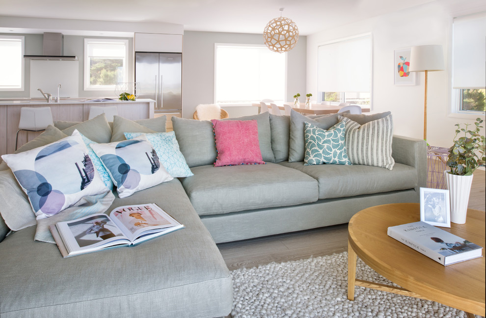 Design ideas for a mid-sized scandinavian open concept family room in Auckland with multi-coloured walls, light hardwood floors and a freestanding tv.