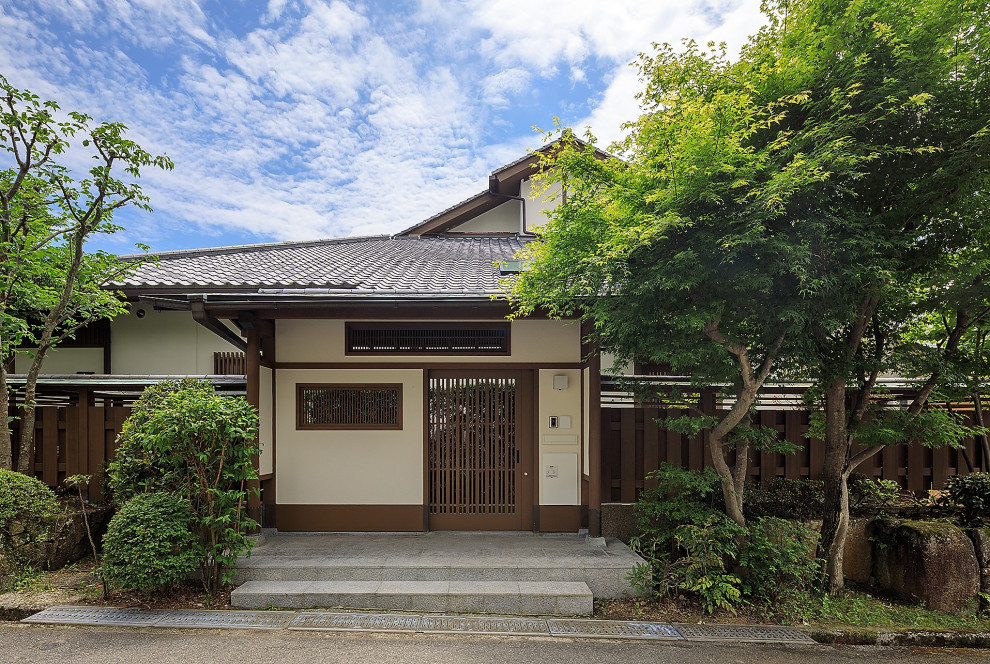Großer Asiatischer Eingang mit weißer Wandfarbe, Granitboden, Schiebetür, brauner Haustür, grauem Boden und Holzdecke in Osaka