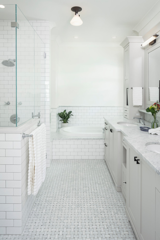 This is an example of a mid-sized traditional master bathroom in Detroit with shaker cabinets, grey cabinets, a drop-in tub, a corner shower, a one-piece toilet, white tile, subway tile, white walls, marble floors, an undermount sink, engineered quartz benchtops, grey floor, a hinged shower door, grey benchtops, a shower seat, a double vanity and a built-in vanity.