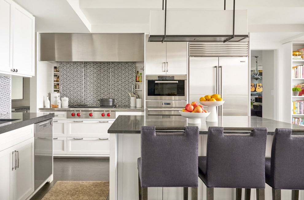 Transitional u-shaped eat-in kitchen in Chicago with soapstone benchtops, mosaic tile splashback, stainless steel appliances, an undermount sink, shaker cabinets, white cabinets, grey splashback, dark hardwood floors, with island and brown floor.