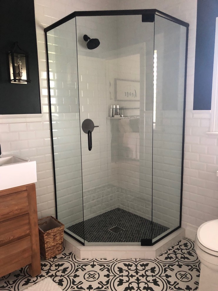 Inspiration for a small country bathroom in Chicago with furniture-like cabinets, light wood cabinets, a corner shower, a one-piece toilet, white tile, ceramic tile, black walls, ceramic floors, a trough sink, black floor and a hinged shower door.