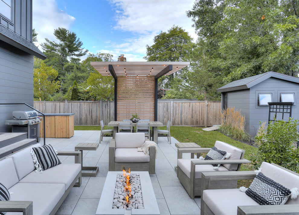 Inspiration for a mid-sized transitional backyard stone patio remodel in Bridgeport with a fire pit and a pergola