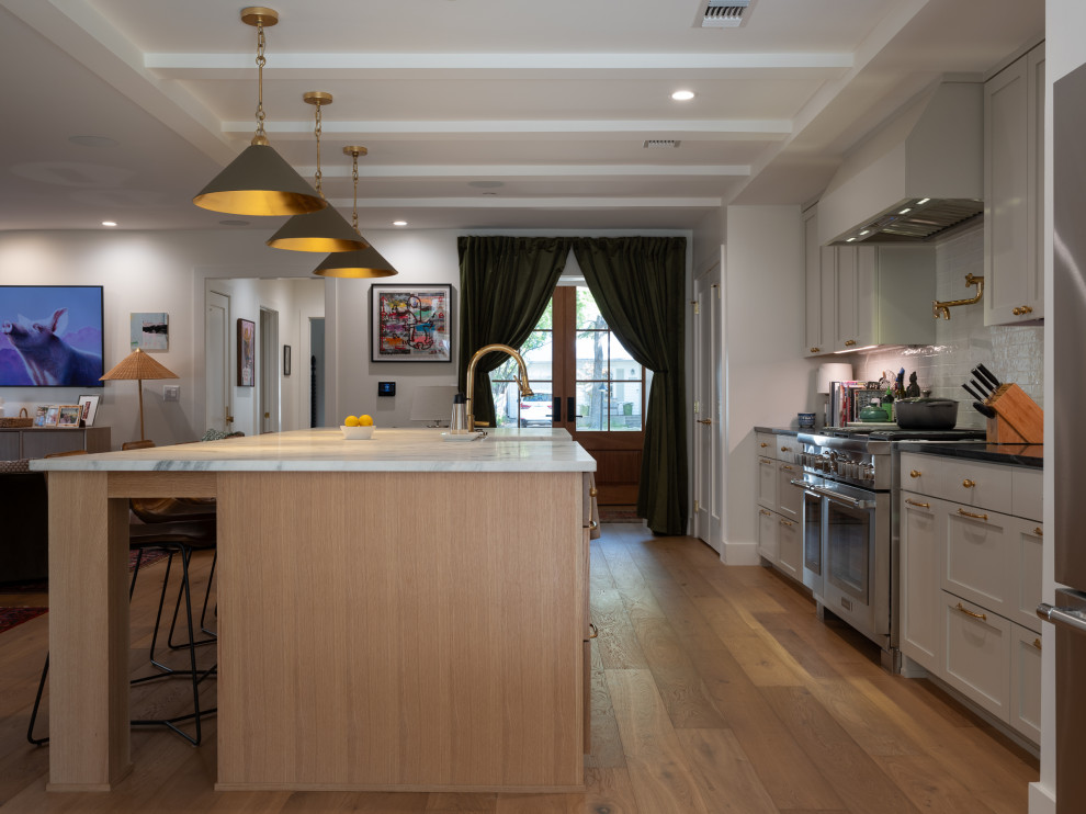 Eat-in kitchen - mid-sized transitional galley medium tone wood floor and coffered ceiling eat-in kitchen idea in Austin with flat-panel cabinets, white cabinets, stainless steel appliances, an island and white countertops
