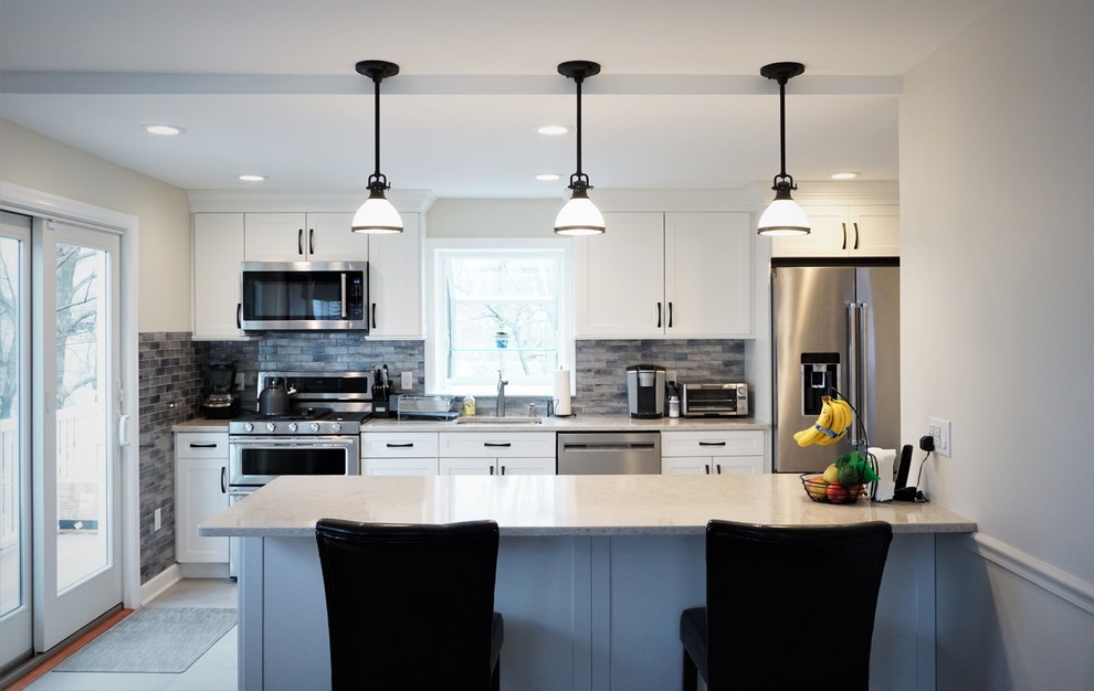 Mid-sized transitional single-wall porcelain tile and gray floor eat-in kitchen photo in New York with an undermount sink, shaker cabinets, white cabinets, quartz countertops, blue backsplash, glass tile backsplash, stainless steel appliances, a peninsula and beige countertops