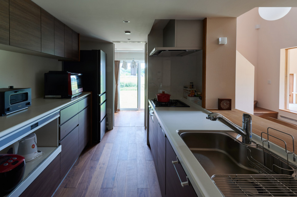 Immagine di una grande cucina lineare moderna chiusa con lavello sottopiano, ante in legno bruno, top in superficie solida, paraspruzzi grigio, pavimento in compensato, penisola e top bianco