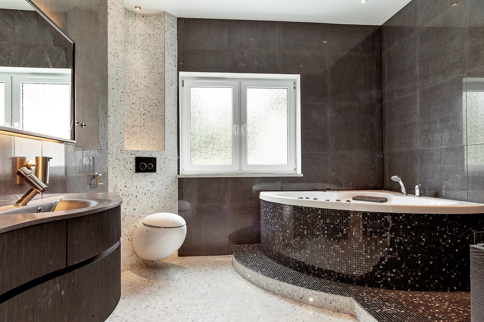 Large contemporary master bathroom in Malmo with dark wood cabinets, a hot tub, a wall-mount toilet, black tile, gray tile, white tile, grey walls, an integrated sink, mosaic tile, mosaic tile floors, stainless steel benchtops and flat-panel cabinets.