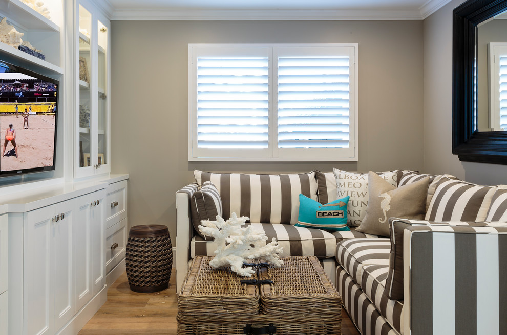 Photo of a small beach style enclosed family room in Orange County with grey walls, light hardwood floors and a built-in media wall.