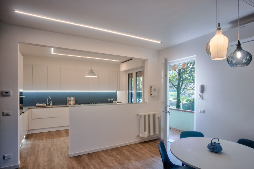 Photo of a mid-sized contemporary l-shaped eat-in kitchen in Other with an undermount sink, flat-panel cabinets, white cabinets, quartzite benchtops, blue splashback, porcelain splashback, stainless steel appliances, vinyl floors, no island, beige floor and grey benchtop.