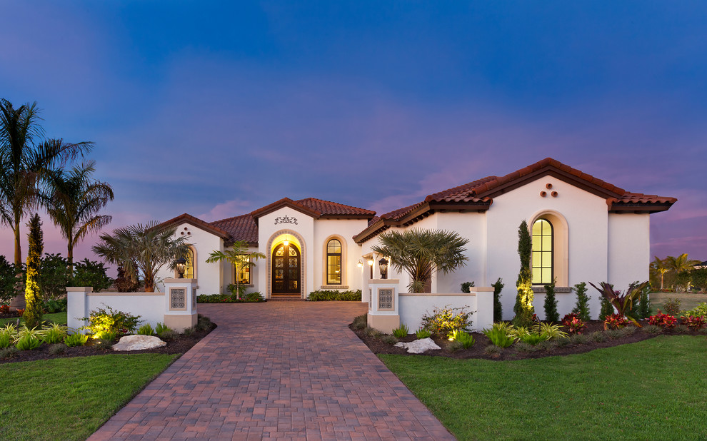 Design ideas for an expansive mediterranean one-storey stucco white house exterior in Tampa with a hip roof and a tile roof.