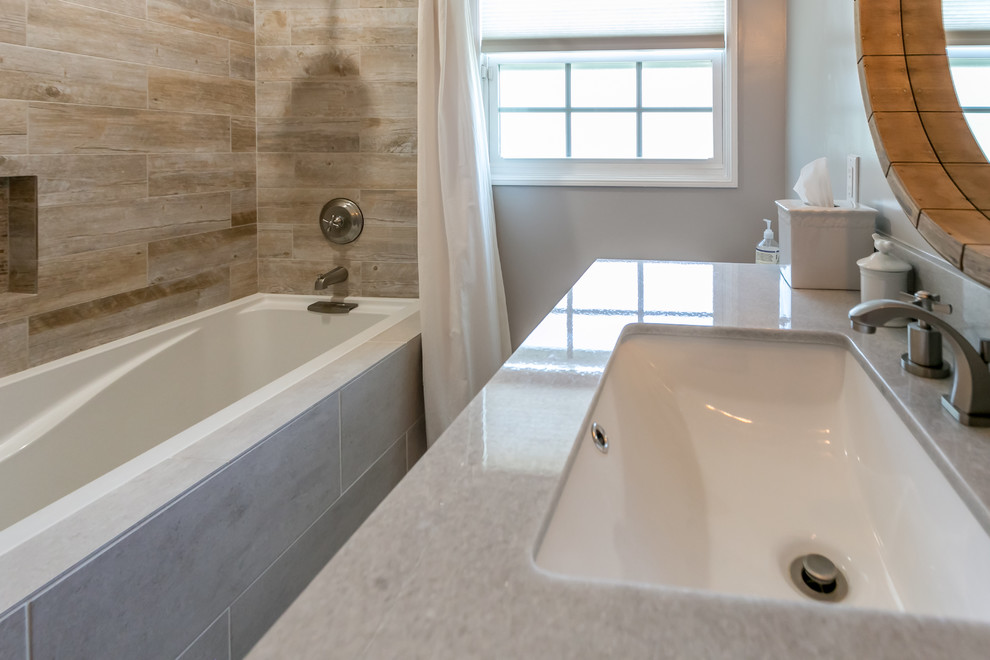 Inspiration for a mid-sized beach style 3/4 bathroom in Los Angeles with furniture-like cabinets, medium wood cabinets, an alcove tub, a shower/bathtub combo, a two-piece toilet, brown tile, gray tile, porcelain tile, grey walls, an undermount sink and quartzite benchtops.
