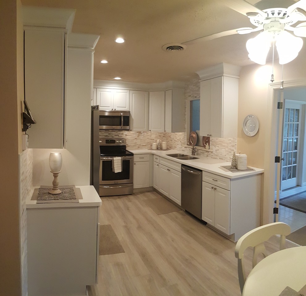Inspiration for a small l-shaped eat-in kitchen remodel with an undermount sink, raised-panel cabinets, white cabinets, quartz countertops, white backsplash, porcelain backsplash, stainless steel appliances and no island