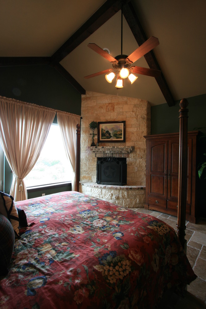 Inspiration for a large traditional master bedroom in Austin with green walls, travertine floors, a corner fireplace, a stone fireplace surround and brown floor.