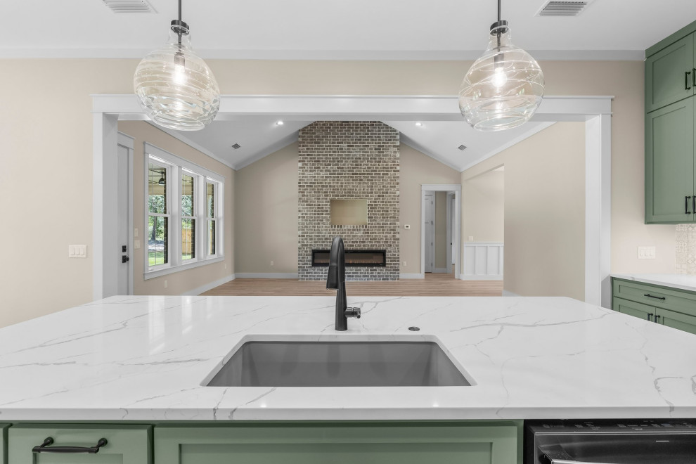 Inspiration for a craftsman l-shaped vinyl floor and beige floor open concept kitchen remodel with an undermount sink, shaker cabinets, green cabinets, quartzite countertops, beige backsplash, porcelain backsplash, stainless steel appliances, an island and white countertops