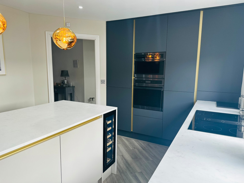 Inspiration for a medium sized modern grey and cream l-shaped kitchen/diner with an integrated sink, flat-panel cabinets, beige cabinets, quartz worktops, white splashback, engineered quartz splashback, black appliances, medium hardwood flooring, an island, brown floors, white worktops and feature lighting.