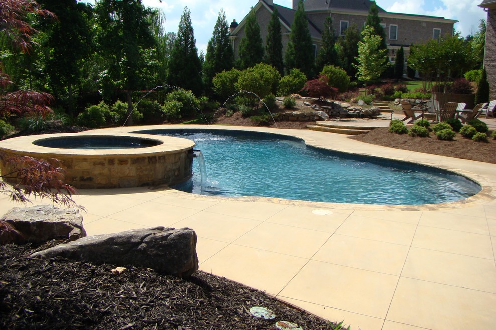 This is an example of a large traditional backyard custom-shaped pool in Atlanta with a water feature.