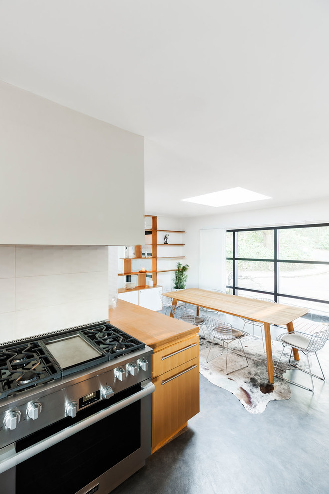 Photo of a large midcentury u-shaped separate kitchen in Portland with an undermount sink, flat-panel cabinets, light wood cabinets, wood benchtops, stainless steel appliances, concrete floors, with island, grey floor and brown benchtop.