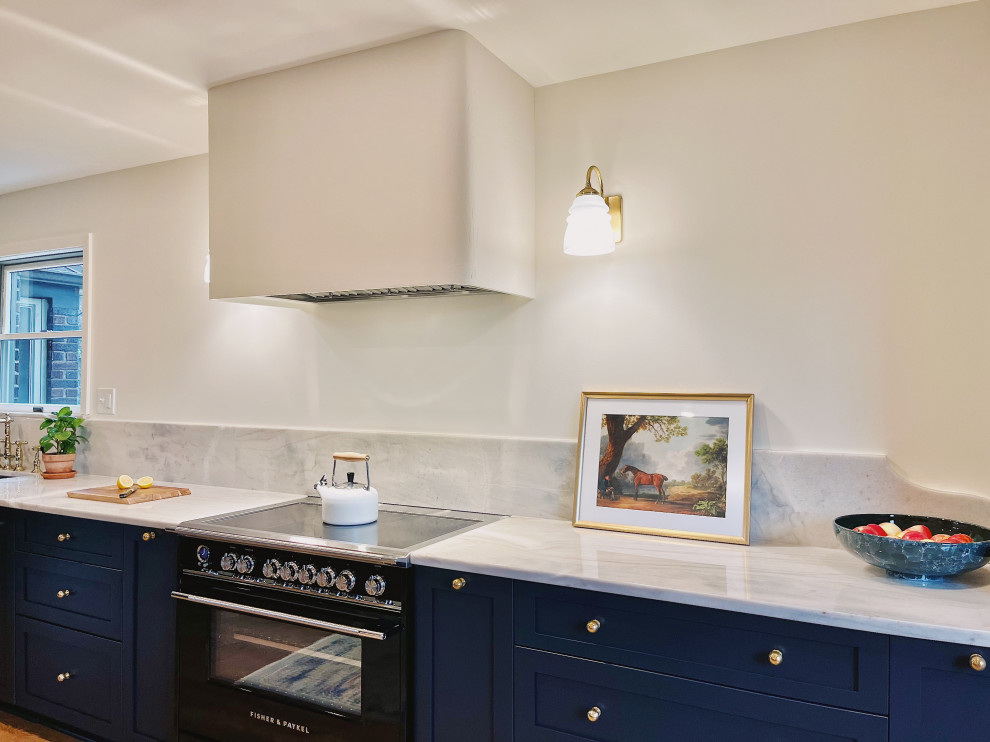 Example of a large transitional l-shaped medium tone wood floor and brown floor eat-in kitchen design with an undermount sink, shaker cabinets, blue cabinets, quartzite countertops, stone slab backsplash, paneled appliances, no island and gray countertops