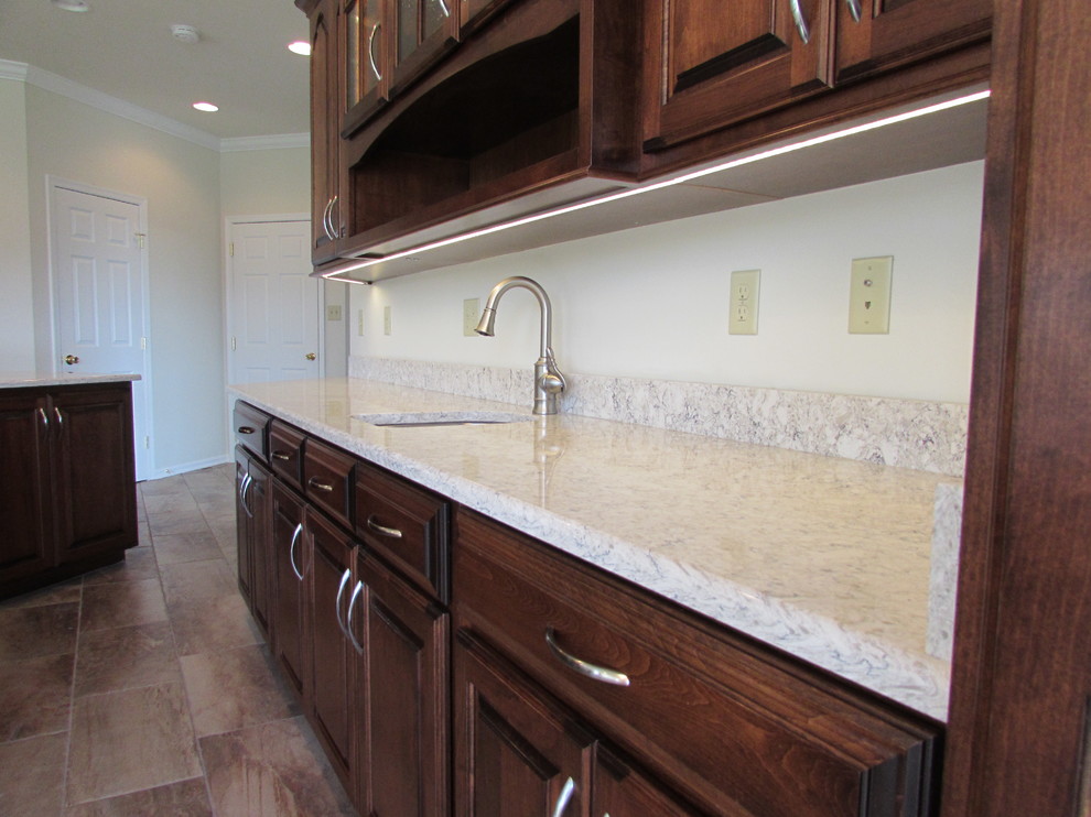 Inspiration for a large transitional galley ceramic tile kitchen pantry remodel in DC Metro with a farmhouse sink, raised-panel cabinets, dark wood cabinets, granite countertops, stainless steel appliances and an island