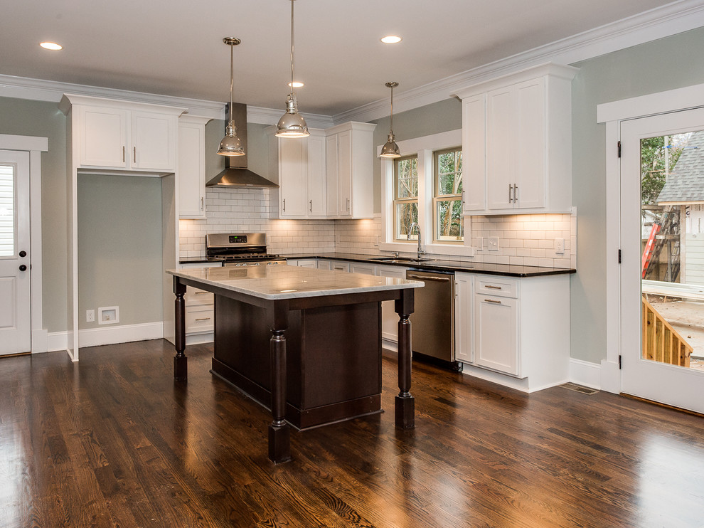 Open concept kitchen - mid-sized transitional l-shaped open concept kitchen idea in Charlotte with an undermount sink, white cabinets, granite countertops, white backsplash, subway tile backsplash, stainless steel appliances and an island
