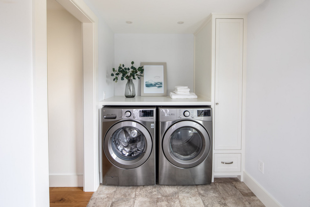 Inspiration for a small beach style single-wall dedicated laundry room in Boston with a side-by-side washer and dryer, blue walls, multi-coloured floor, white benchtop, recessed-panel cabinets, white cabinets, wood benchtops and ceramic floors.
