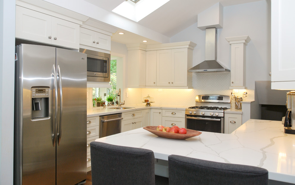 Mid-sized transitional u-shaped dark wood floor eat-in kitchen photo in Boston with an undermount sink, shaker cabinets, white cabinets, quartz countertops, gray backsplash, glass tile backsplash, stainless steel appliances and a peninsula