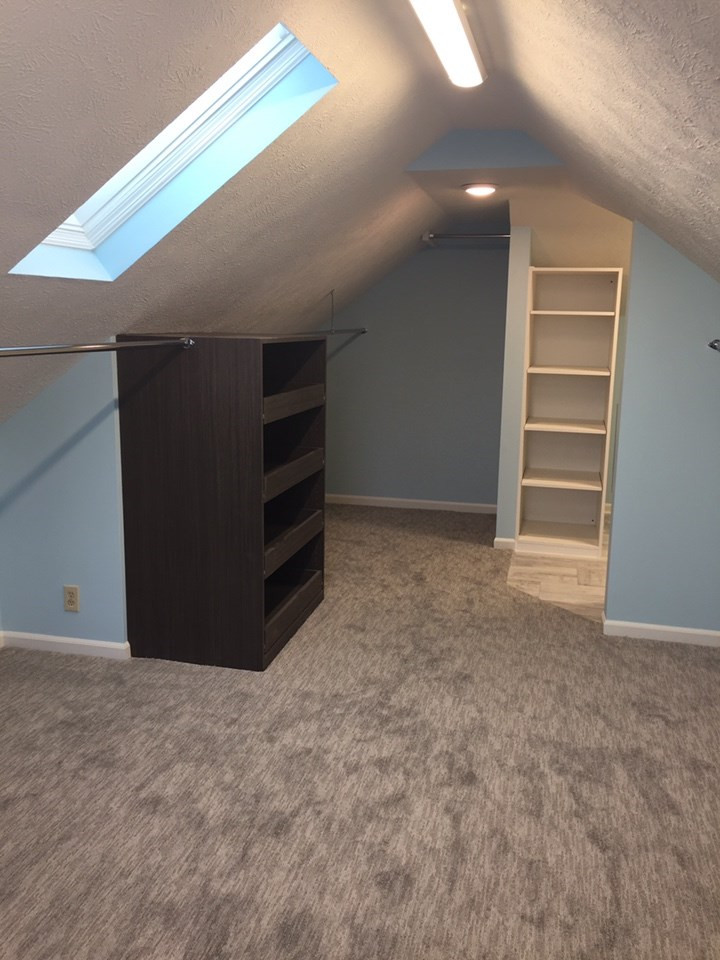 Photo of a contemporary gender-neutral walk-in wardrobe in Other with open cabinets, dark wood cabinets, carpet and grey floor.