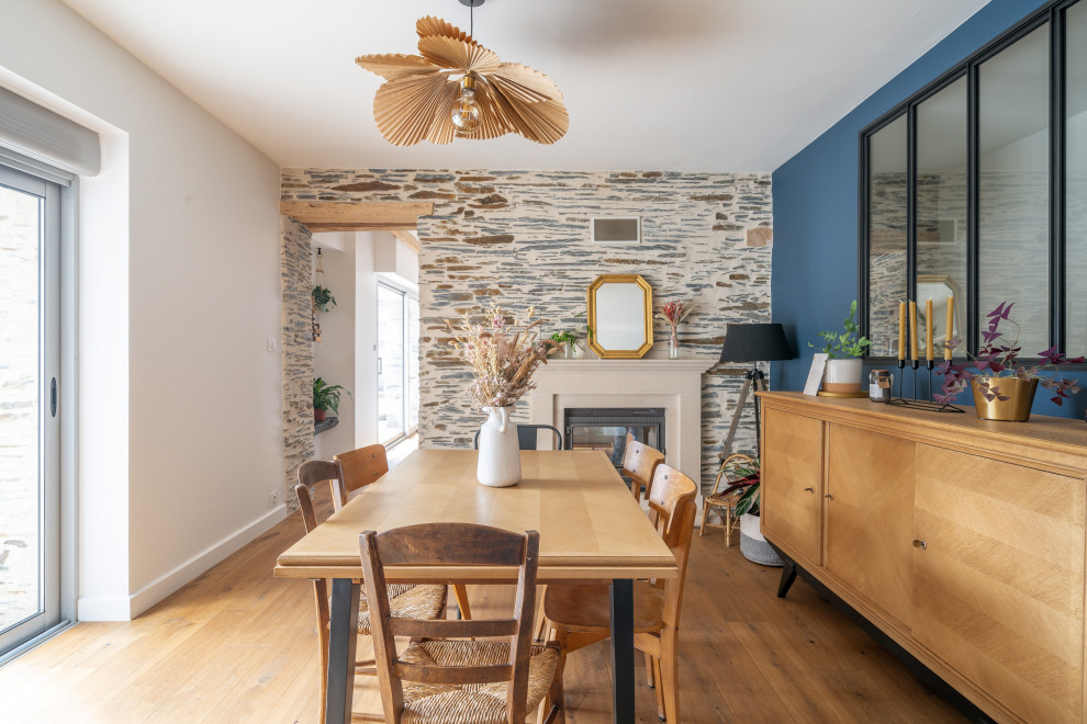 Foto de comedor de estilo de casa de campo de tamaño medio abierto con paredes azules, suelo de madera clara, todas las chimeneas, suelo marrón, vigas vistas y ladrillo