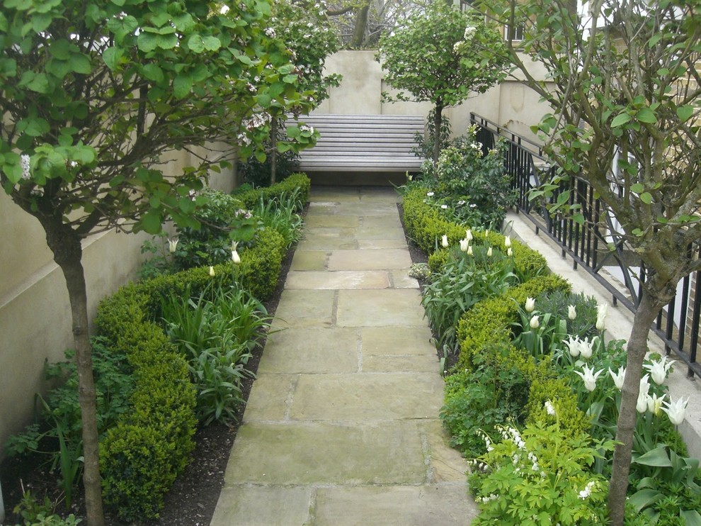 This is an example of a mid-sized transitional courtyard driveway in Madrid with a garden path and natural stone pavers.
