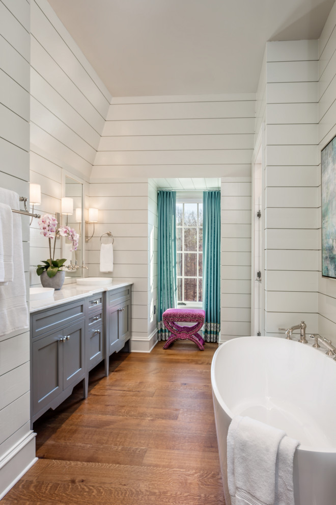 Design ideas for a transitional bathroom in Other with shaker cabinets, grey cabinets, a freestanding tub, white walls, dark hardwood floors, a vessel sink, brown floor, white benchtops, a double vanity, a built-in vanity and planked wall panelling.