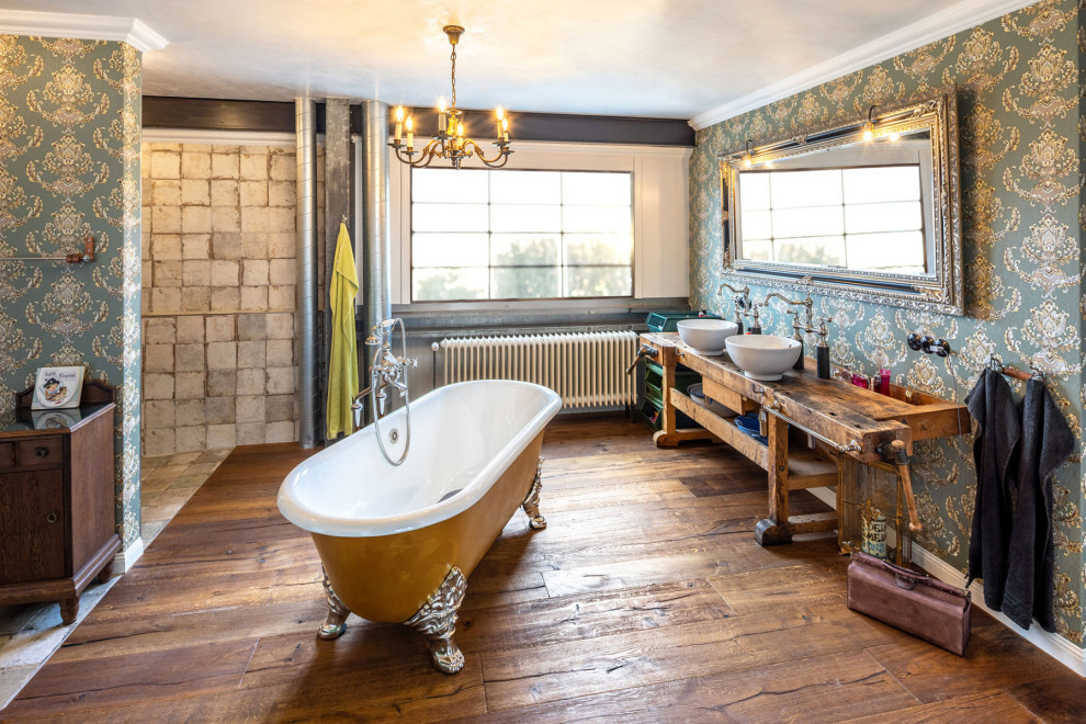 Badezimmer mit freistehender Badewanne, offener Dusche, Wandtoilette mit Spülkasten, Aufsatzwaschbecken, Waschtisch aus Holz, Wandnische, Doppelwaschbecken und freistehendem Waschtisch in Munich