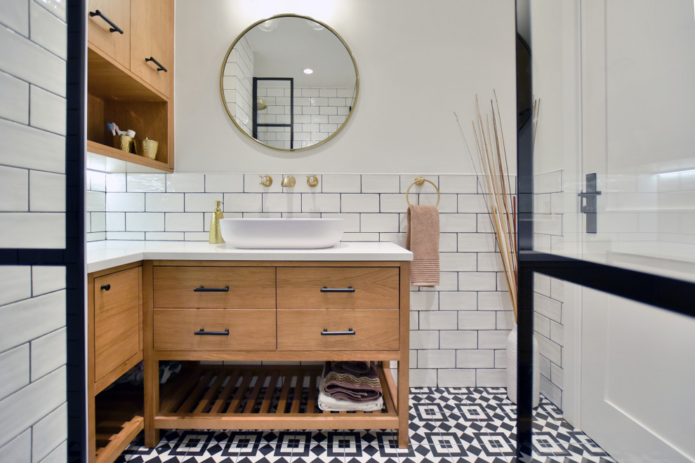 Foto på ett litet rustikt vit en-suite badrum, med bruna skåp, en hörndusch, svart och vit kakel, vita väggar, cementgolv, ett väggmonterat handfat, med dusch som är öppen och släta luckor
