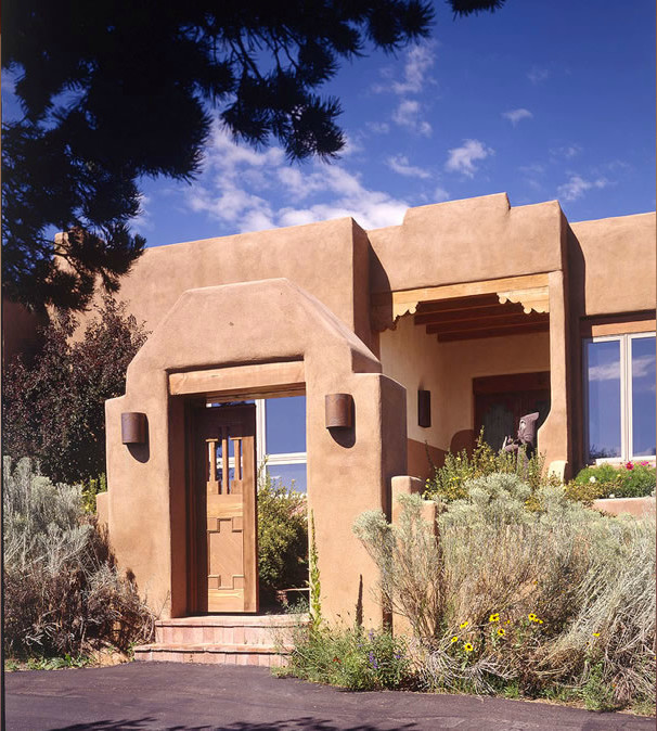 Mid-sized two-storey adobe beige house exterior in Albuquerque with a flat roof.