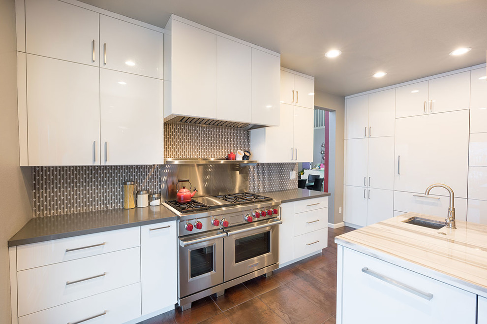 Kitchen - contemporary porcelain tile and brown floor kitchen idea with flat-panel cabinets, white cabinets, gray backsplash, stainless steel appliances and an island
