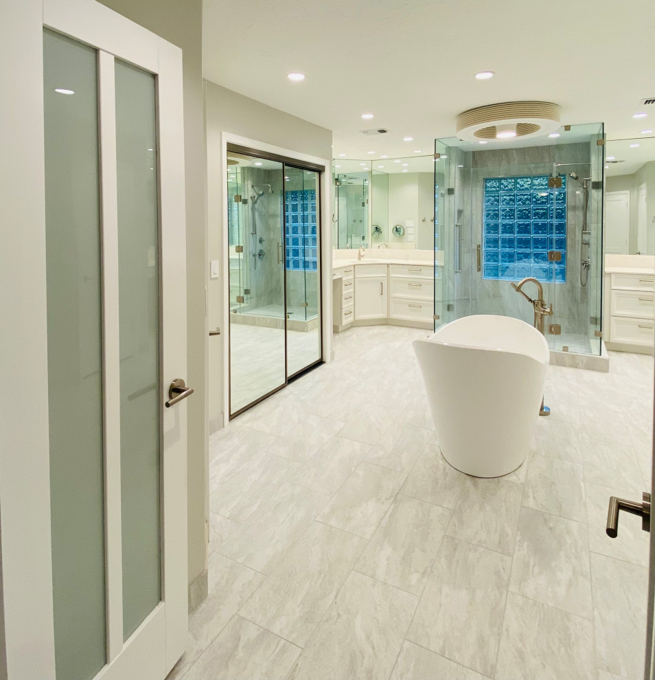 Photo of an expansive modern ensuite bathroom in Houston with recessed-panel cabinets, white cabinets, a freestanding bath, an alcove shower, porcelain tiles, porcelain flooring, a submerged sink, engineered stone worktops, a hinged door, white worktops, double sinks, a built in vanity unit, an enclosed toilet, grey tiles, grey walls and grey floors.