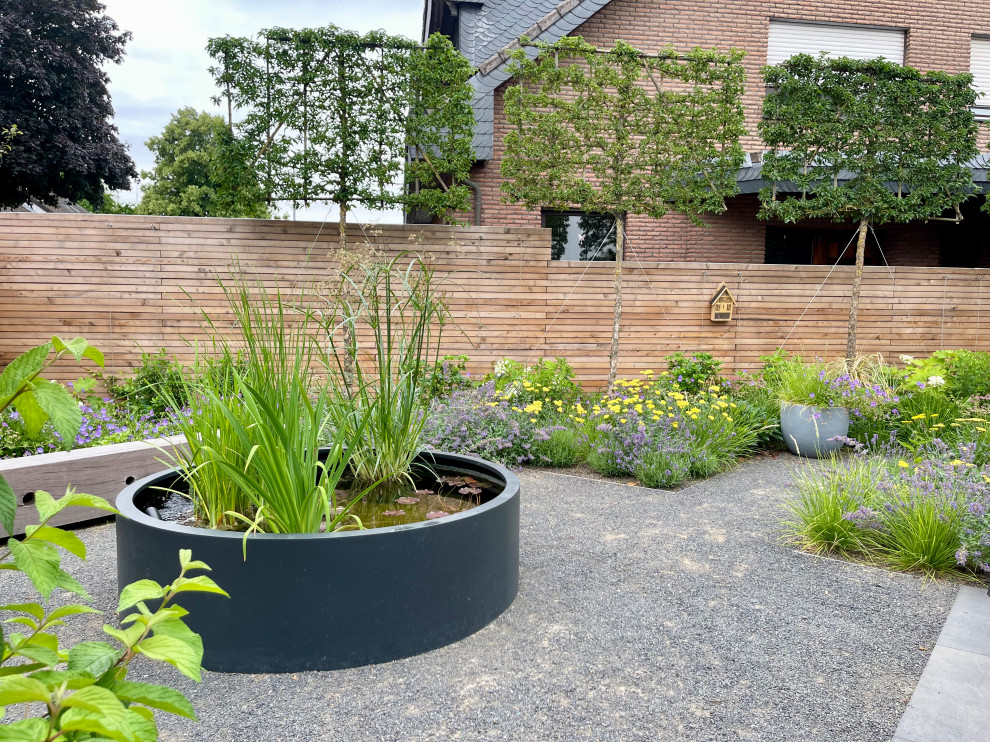 Esempio di un privacy in giardino minimalista esposto in pieno sole di medie dimensioni e nel cortile laterale in estate con ghiaia e recinzione in legno