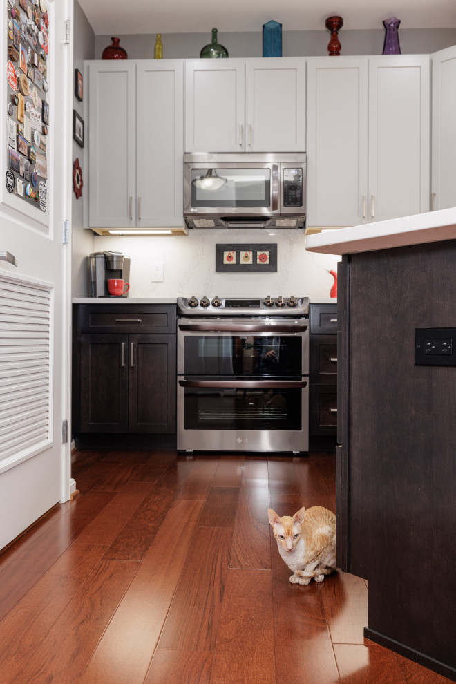 Idéer för att renovera ett mellanstort vintage vit vitt kök, med en undermonterad diskho, skåp i shakerstil, grå skåp, bänkskiva i kvarts, vitt stänkskydd, stänkskydd i sten, svarta vitvaror, mellanmörkt trägolv, en halv köksö och orange golv