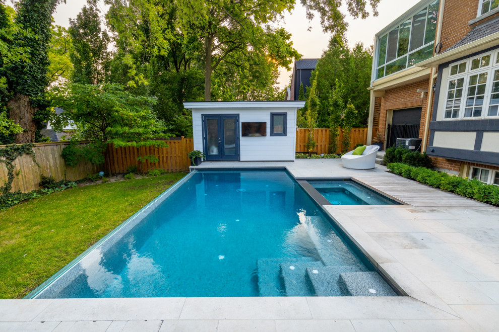 Diseño de casa de la piscina y piscina infinita tradicional renovada pequeña rectangular en patio trasero con adoquines de piedra natural