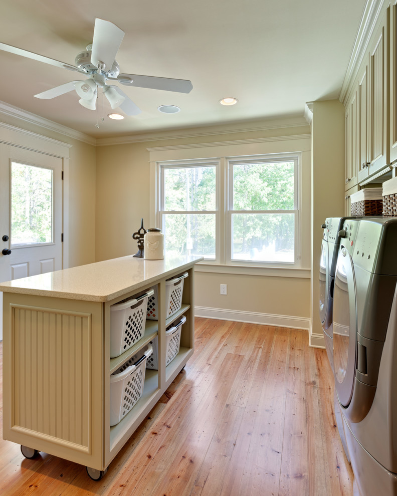Design ideas for an expansive country u-shaped dedicated laundry room in Atlanta with an undermount sink, recessed-panel cabinets, green cabinets, quartz benchtops, beige walls, medium hardwood floors, a side-by-side washer and dryer, brown floor and white benchtop.