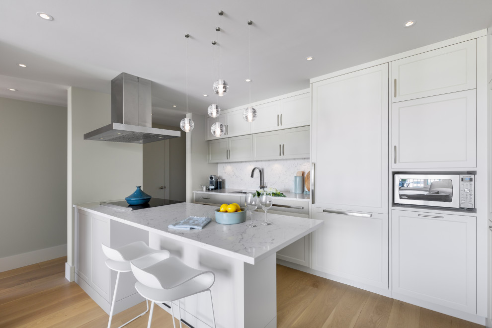 Inspiration for a small transitional brown floor kitchen remodel in Vancouver with a drop-in sink, shaker cabinets, white cabinets, white backsplash, stainless steel appliances, white countertops and an island